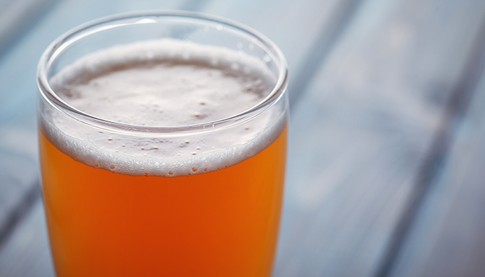 hazy orange beer closeup with a blurred wooden table backdrop
