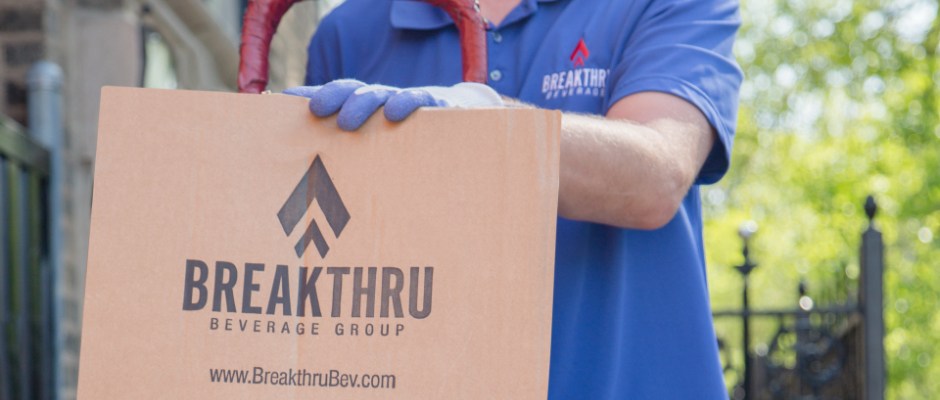 delivery driver places his hand on a cardboard breakthru beverage box