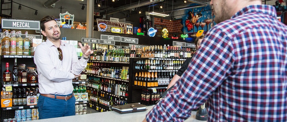 salesman talks with a customer out of view in a liquor store