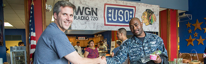fair skin man in a grey tee and dark skin military man shaking hands
