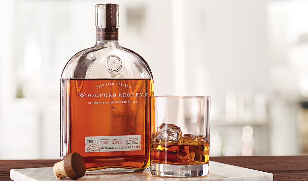 Golden Brown Bottle of Woodford Reserve perched on table with a white splash background