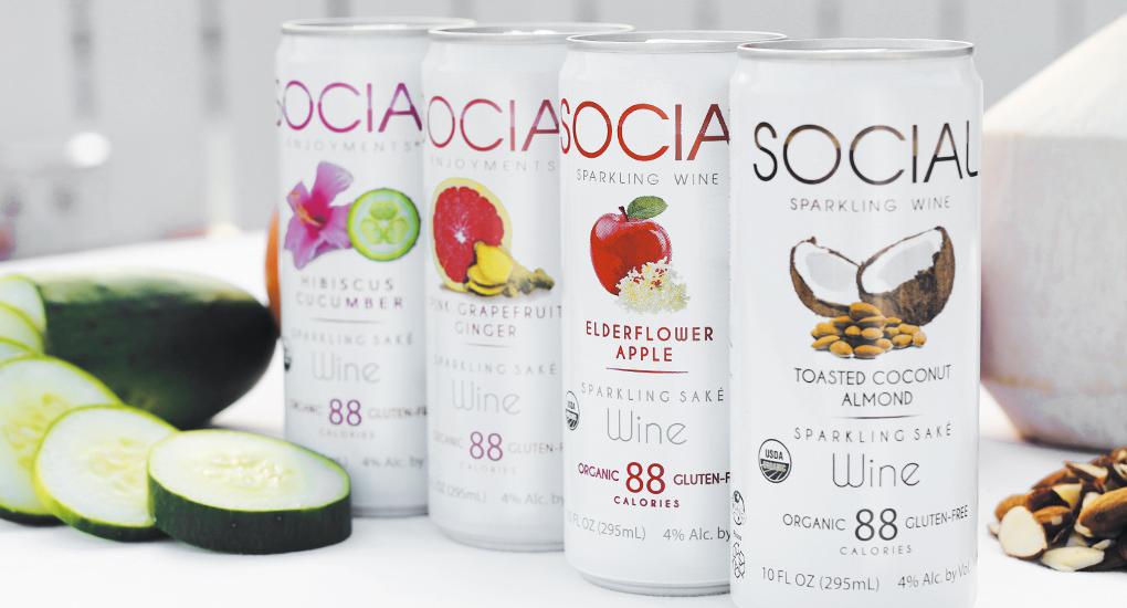 four white cans of SOCIAL wine framed by cucumbers and almonds