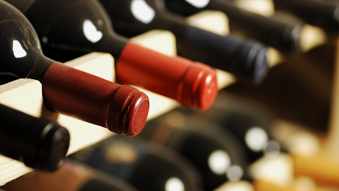row wine bottles arranged on a wooden rack