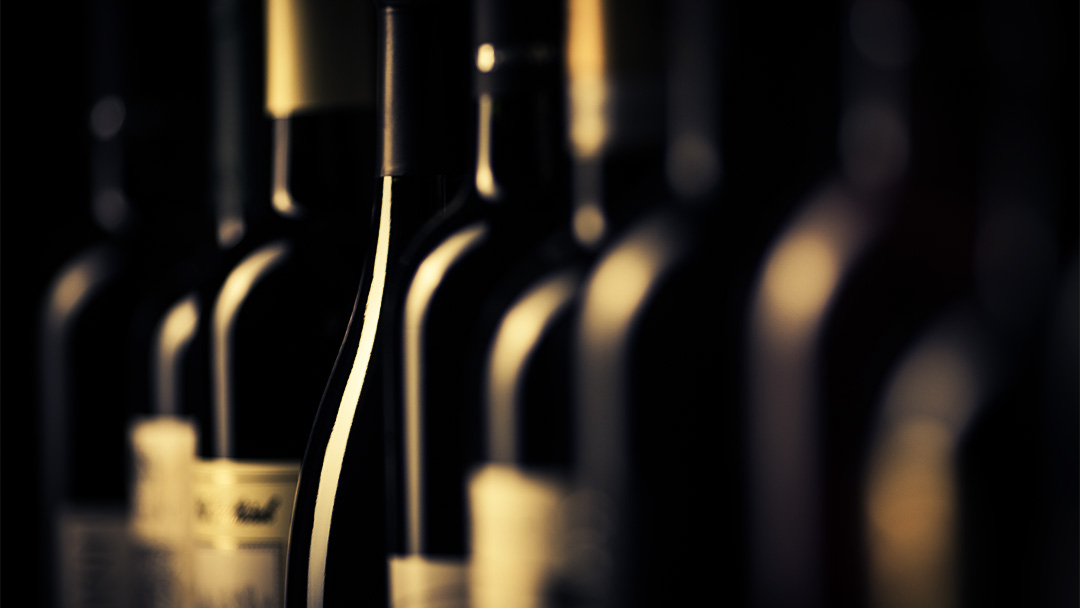 row of dark wine bottles in low lighting