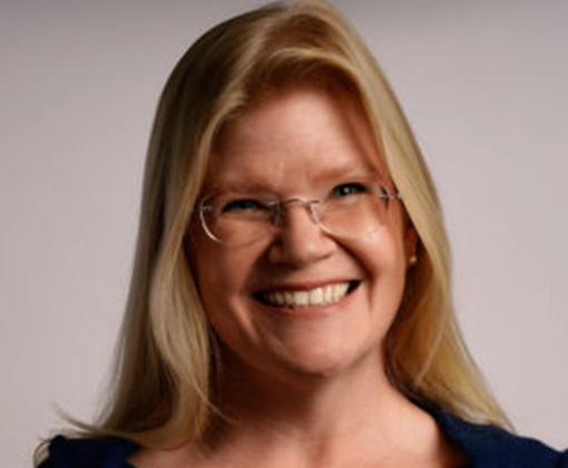 kryss speegle - smiling woman in glasses and navy blue top against a white background